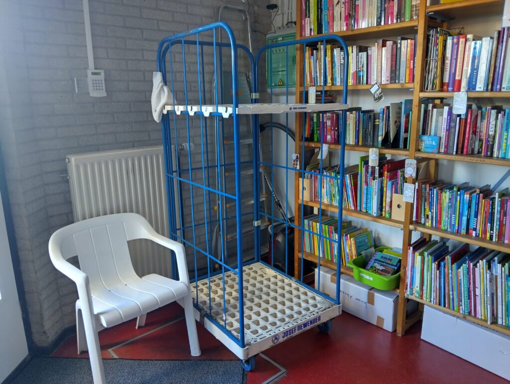 Rolcontainer voor ingebrachte spullen naast de kinderboeken