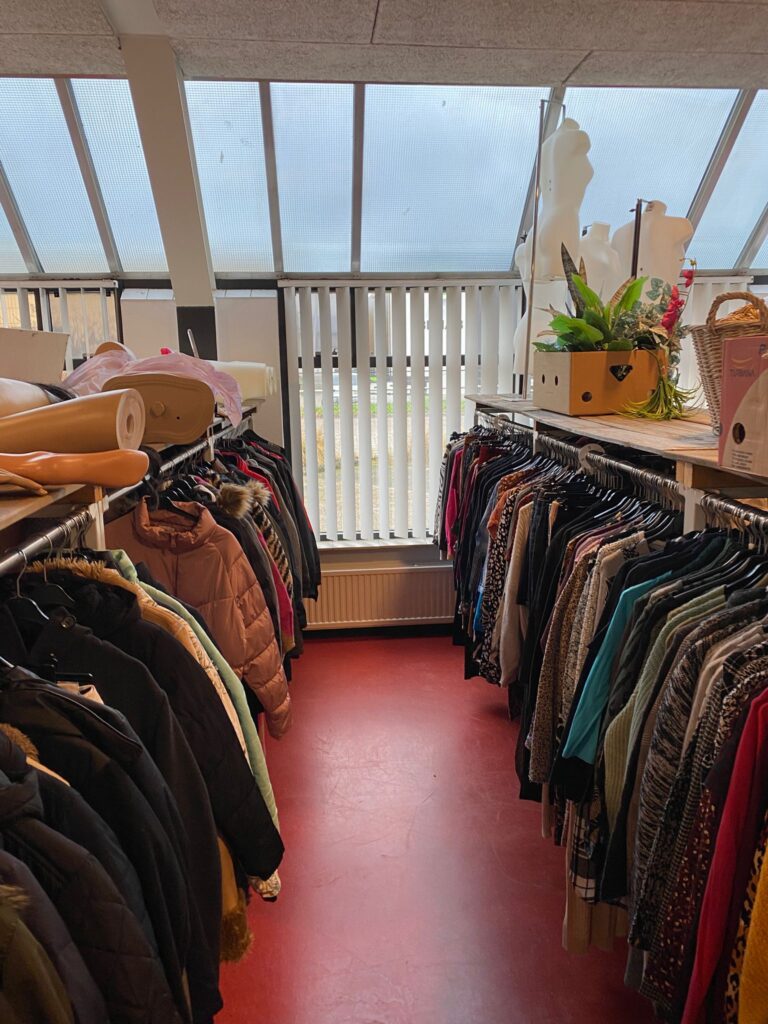 Kledingrekken met jassen en truien in de Weggeefschuur